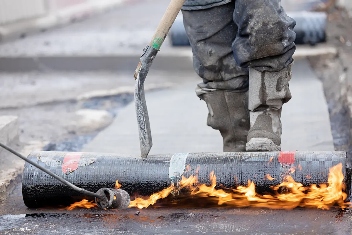 Close-up of a modified bitumen roll being heat-welded during installation