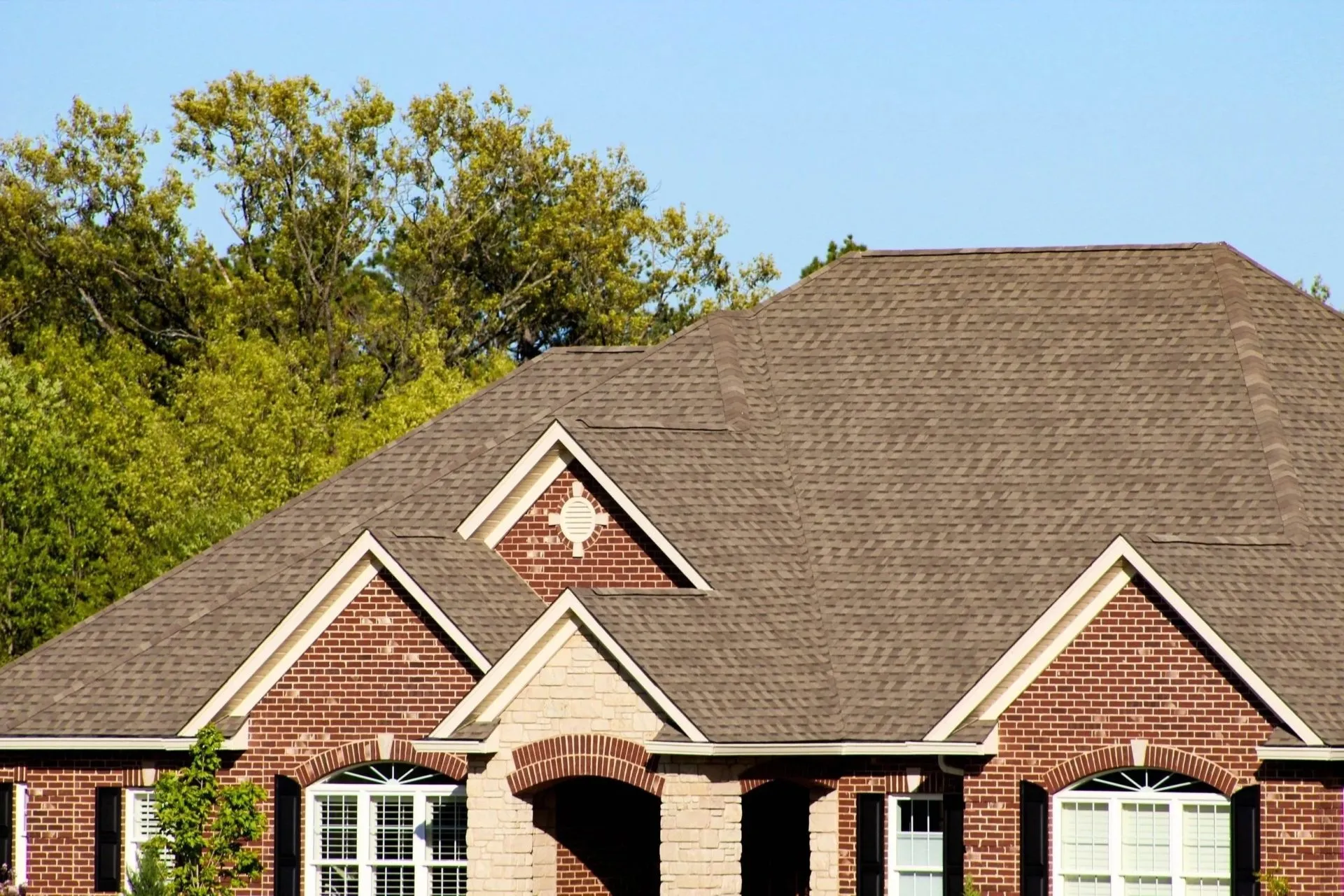 Brick home with multiple gables and a tan architectural shingle roof