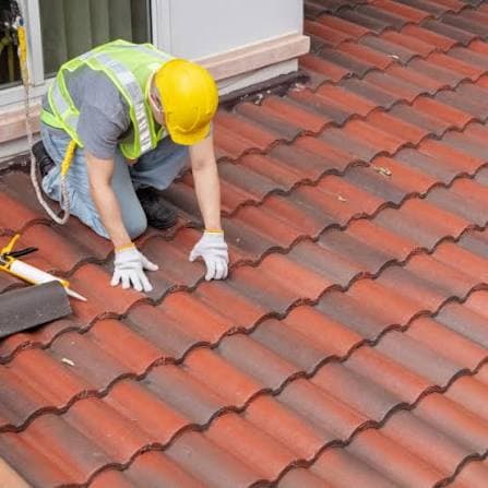 Roofer installing red clay roof tiles