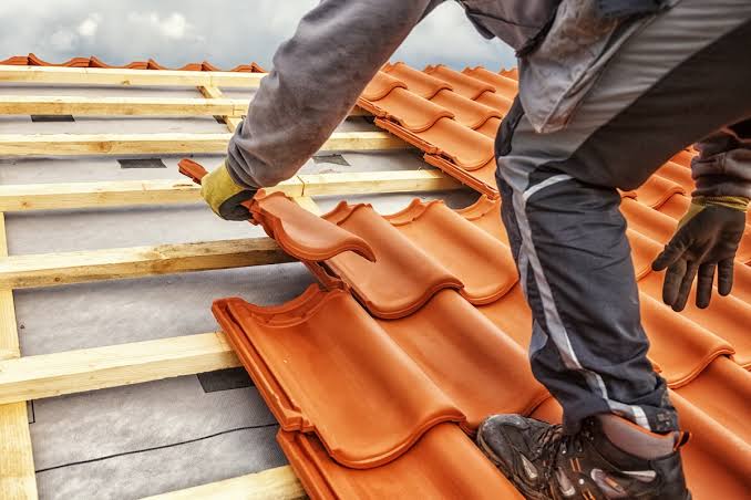 Roofer setting a clay roof tile over battens and underlayment
